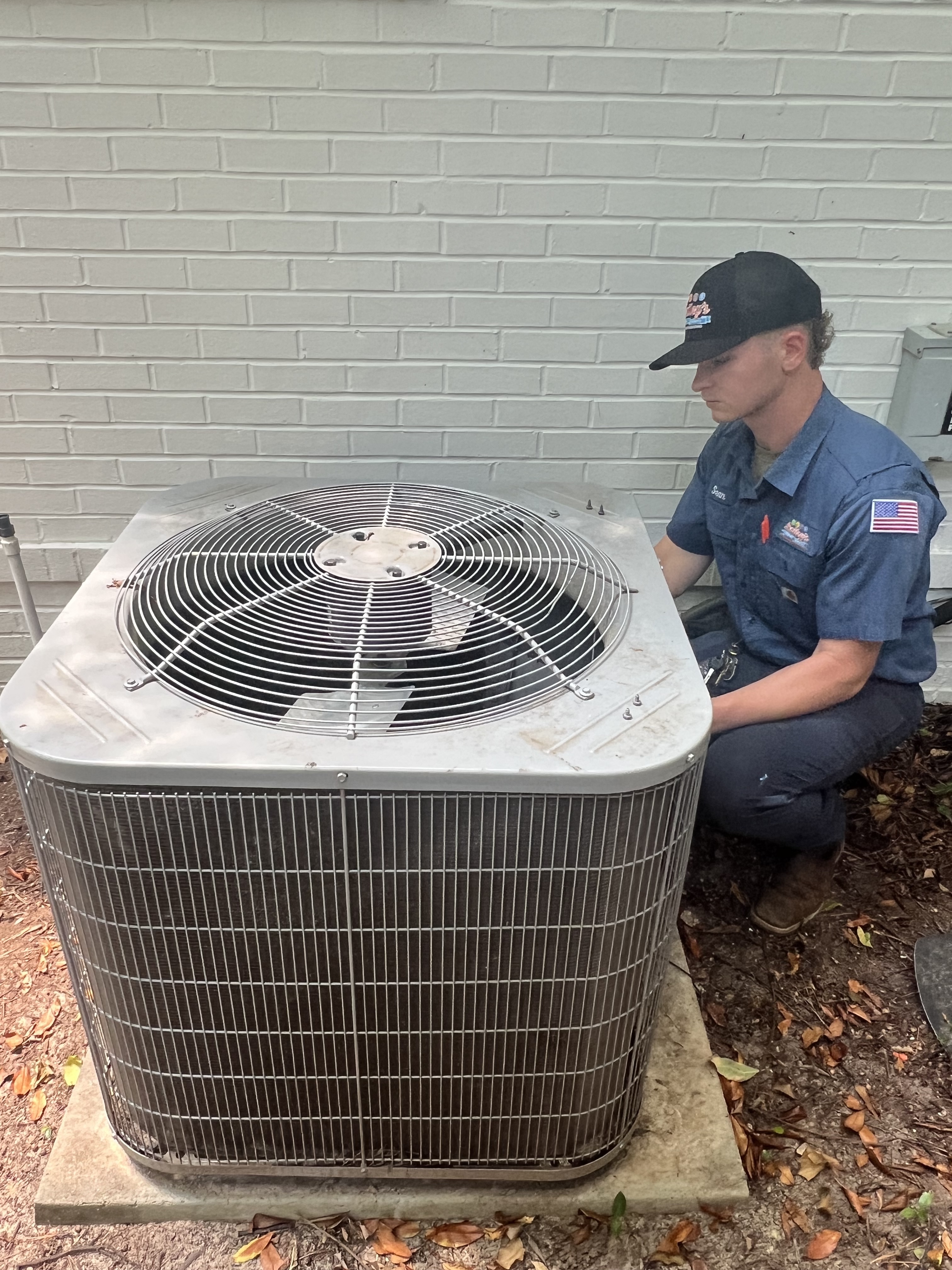 A Bailey's technician working on an outdoor AC unit in Augusta